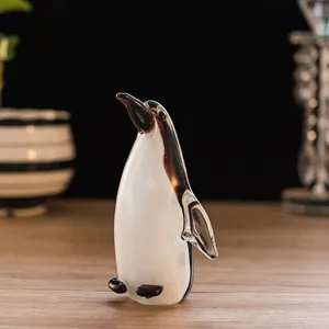 Close-up detail of the glass penguin figurine showing its smooth black and white glazed surface.