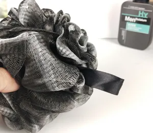 Primo piano dettagliato di una spugna da bagno in rete nera e grigia con texture morbida.