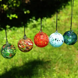 Close-up of colorful blown glass hanging balls, vibrant swirling patterns in natural sunlight.