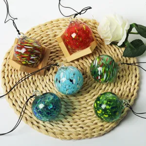 Colorful blown glass suncatcher hanging ornaments detail with wooden stand and straw mat.