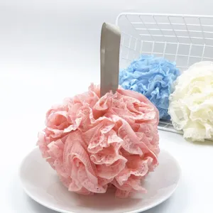 Primer plano detallado de una esponja de baño de malla rosa con encaje en un plato blanco.