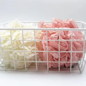 Primer plano detallado de esponjas de baño de encaje rosa y crema en una bonita cesta.