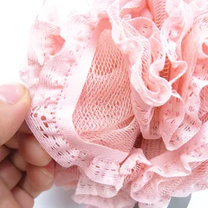 Primer plano detallado de esponja de baño de malla rosa esponjosa con delicado borde de encaje.