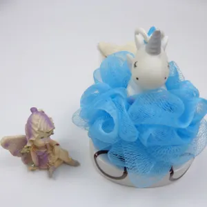 Close-up detail of the cute unicorn blue bath sponge mesh loofah with fairy figurine decor.