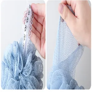 Close-up detail view of soft mesh shower puff with delicate lace tag showing fine texture.