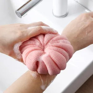 Pink mesh bath sponge for body washing, showing soft foaming texture in bathroom use.