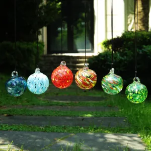 Close-up view of colorful hand-blown glass hanging sun catcher spheres displayed in outdoor garden.