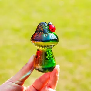 Primo piano dettagliato di una statuetta di fungo in vetro colorato con una coccinella.