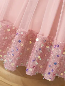 Dettaglio abito da principessa per bambina in tulle e paillettes rosa per feste eleganti.