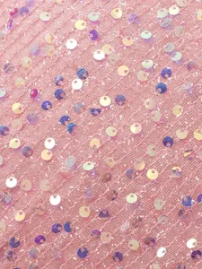 Primo piano dettaglio tessuto tulle paillettes rosa, materiale rete scintillante per vestito.