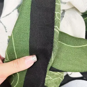 Gros plan sur la texture du tissu en coton et lin, motif de plantes et bordure contrastée.