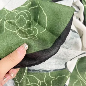 Vue rapprochée montrant la texture douce coton-lin et le motif camélia vert de l'écharpe.