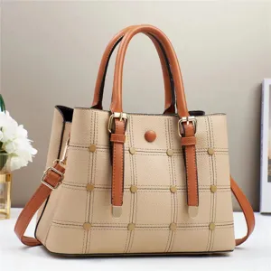 Detailansicht der beigen PU-Lederhandtasche mit braunen Griffen, Steppgitter und Metallschnallen.