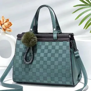Gedetailleerd overzicht van groen geruite tas met pluche pompon hanger en dubbele handgrepen.
