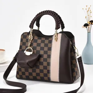 Vista dettagliata della borsa a tracolla a quadretti marrone con manico intrecciato e mini pochette.