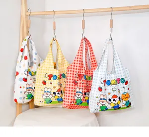 Detailed view of casual canvas tote shopping bags hanging on wooden rack with cute cartoon prints.