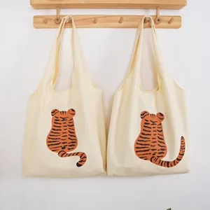 Detailed view of beige canvas tote bags featuring cute cartoon tiger print on wall rack.