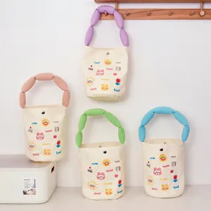 Canvas bucket bag detail showing colorful handles and cute embroidered cartoon patterns.