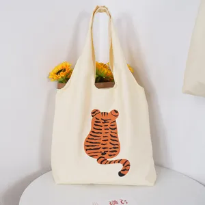 Canvas tote bag detail showing cute tiger back graphic and sunflower prop in a clean setup.