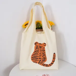 Close up of aesthetic canvas tote bag featuring a cute cartoon tiger back print design.