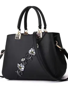 Elegante bolso de mano negro para mujer con bordado floral, asa superior y correa de hombro.