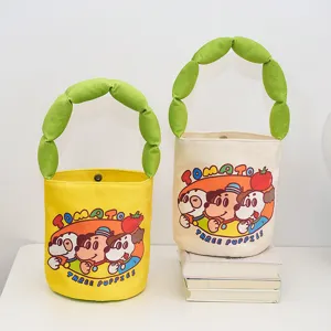 Detailed shot of canvas bucket bag with green stuffed handle and cute cartoon dog print graphic.