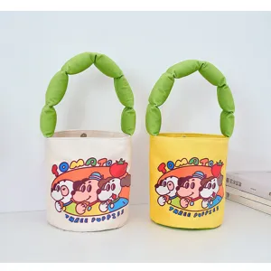 Canvas bucket bag with cute stuffed green handle and playful cartoon dog print for daily casual use.