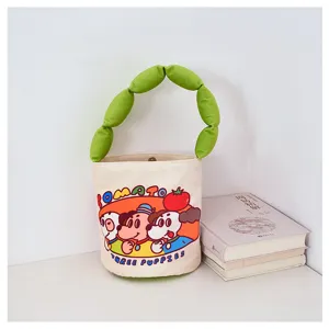 Cute cartoon canvas bucket bag with green puffy handle, stylish shoulder handbag for daily wear.