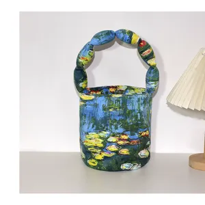 Artistic canvas bucket bag with unique padded round handle and classic oil painting print.