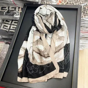 Vue détaillée du motif floral de camélia noir et blanc sur un tissu d'écharpe doux.