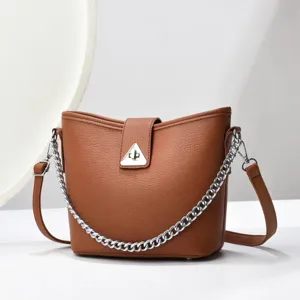 Sac seau marron minimaliste avec bandoulière chaîne argentée et serrure triangulaire.