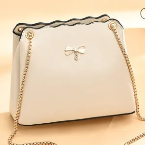 Sac à bandoulière beige chic pour femme avec chaîne dorée élégante et joli nœud papillon.