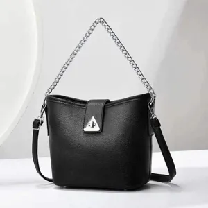 Vue détaillée du sac seau en cuir noir avec poignée chaîne argentée et fermoir triangulaire.