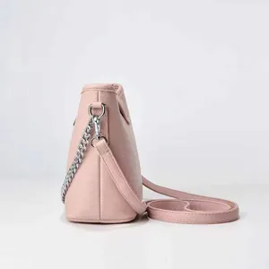 Vue rapprochée du sac seau en cuir rose montrant son profil latéral et sa bandoulière chaîne.