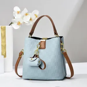 Detailed view of the stylish blue bucket bag with brown handles, gold hardware, and chic pendant.
