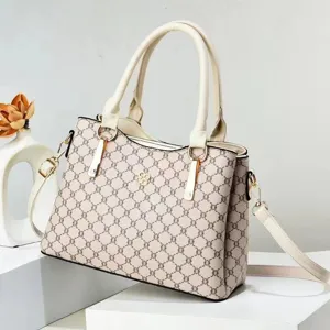 Vista detallada del bolso de mano para mujer elegante con patrón monograma y detalles dorados.