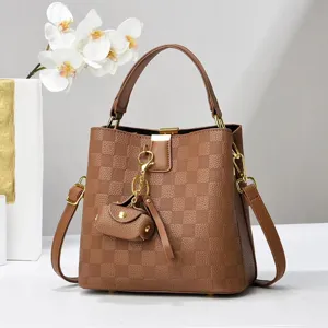 Brown checkered bucket bag with top handle, crossbody strap and chic mini charm. Stylish daily use.