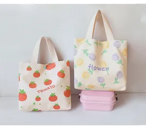 Close-up detail of cute canvas tote bags with tomato and flower print designs for daily use.