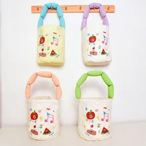 Cute canvas bucket bag with colorful stuffed handle and playful cartoon print, ideal for daily use.