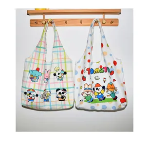 Canvas tote bag detail showing cute cartoon animal prints and plaid patterns on wall.