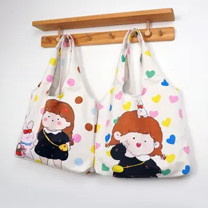 Detail view of cute canvas tote bags with cartoon girl and heart prints hanging on wall rack.