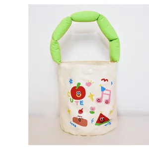 Cute canvas bucket bag with green puffy handle and cartoon print, ideal summer handbag.