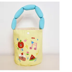 Cute canvas bucket bag detail showing fluffy blue handle and colorful cartoon fruit prints.
