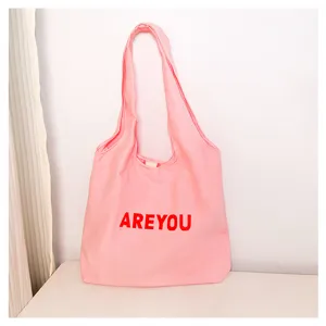 Detail shot of a casual pink canvas tote bag with red letter print for daily commute.