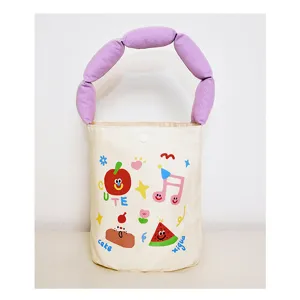 Close-up of canvas bucket bag with cute cartoon prints and unique purple padded handle.