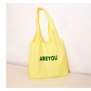 Canvas tote bag detail view, yellow fabric with green AREYOU print, casual daily use style.