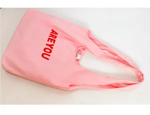 Close-up detail of the pink canvas tote bag featuring stylish red text print and sturdy handles.