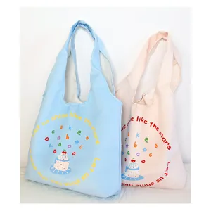 Close-up detail view of cute canvas tote bags in blue and pink with lovely cake print graphics.