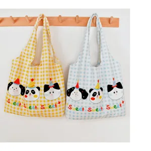 Close-up detail of casual canvas tote bag featuring cute animal prints and yellow blue gingham.