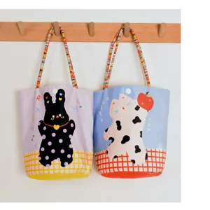 Cute printed flannel tote bag detail showing colorful beaded handles and rabbit cat graphics.